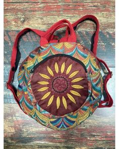 a small purse with a sunflower design on the front and side, sitting on top of a wooden surface