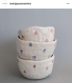 three white bowls stacked on top of each other with blue and red flowers in them