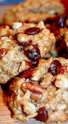 several cookies with nuts and cranberries on a wooden table next to a red cup