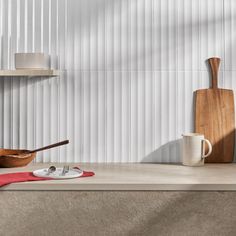 a kitchen counter with wooden utensils on it, and a cutting board next to it