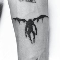 a black and white photo of a person's arm with a bat tattoo on it