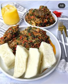 two plates with food on them next to a glass of orange juice