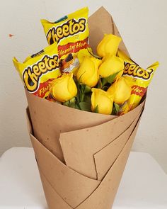 a bouquet of yellow roses wrapped in brown paper and some candy bar wrappers sitting on top of it