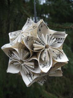 an origami flower made out of sheet music notes hanging from a tree branch