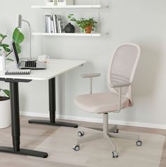 a white desk with a laptop computer on top of it and a plant in the corner