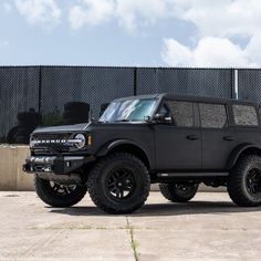 a black truck parked in front of a fence