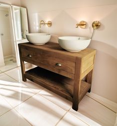 two bowls sit on top of a wooden vanity in a bathroom with white tile flooring