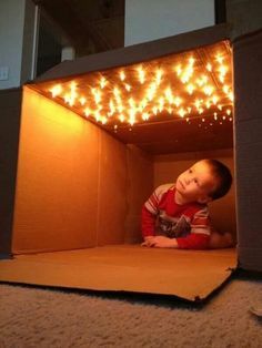 a little boy sitting in a cardboard box with some lights on it and the caption reads