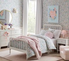 a bedroom with floral wallpaper and bedding in pastel colors, including pink