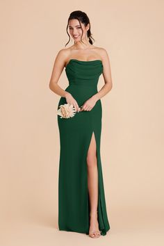 a woman in a long green dress is posing for the camera with her hand on her hip