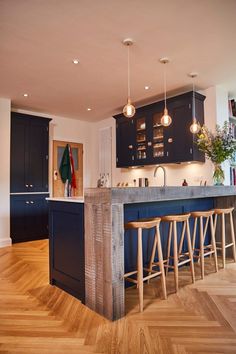 a kitchen with wooden floors and black cabinets