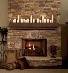 a stone fireplace with candles on the mantle