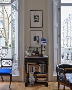 a living room filled with furniture and pictures on the wall next to a doorway that leads to a balcony