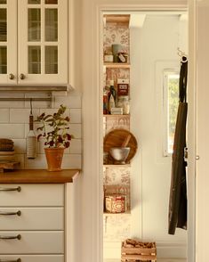 a kitchen with white cupboards and wooden counter tops next to an open pantry door