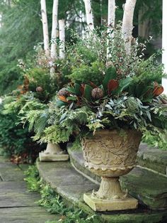 a planter filled with lots of greenery sitting on top of steps next to trees