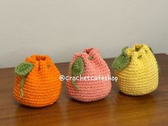 three small crocheted bags sitting on top of a wooden table next to each other