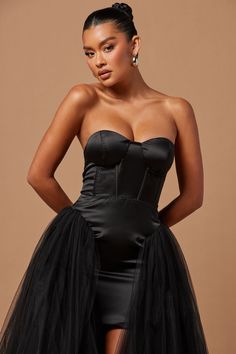 a woman wearing a black dress with a high slit skirt and strapless bustier