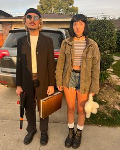 two people standing next to each other in front of a car and holding suitcases