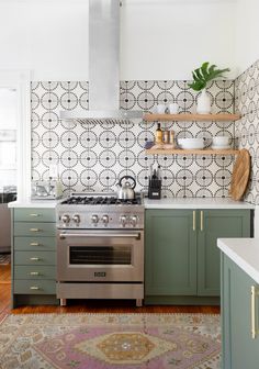 a stove top oven sitting inside of a kitchen next to green cabinets and counter tops