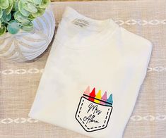 Embroidered Personalized Teacher Crayon Pocket Tee. Perfect for teacher appreciation or birthday gifts! These are comfort colors tees. Relaxed fit. School T-shirt With Embroidered Text And Crew Neck, Casual School T-shirt With Embroidered Graphics, School T-shirt With Embroidered Crew Neck, School Crew Neck Embroidered T-shirt, White T-shirt With Embroidered Logo As Gift, Embroidered Crew Neck T-shirt For School, Embroidered Crew Neck T-shirt, Casual T-shirt With Custom Embroidery As Gift, Casual Custom Embroidery T-shirt As Gift