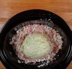 a black bowl filled with chopped vegetables on top of a wooden table