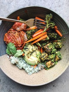 a bowl filled with broccoli, carrots and other vegetables on top of rice