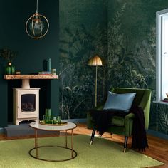 a living room with green wallpaper and a white fire place in the corner next to a couch