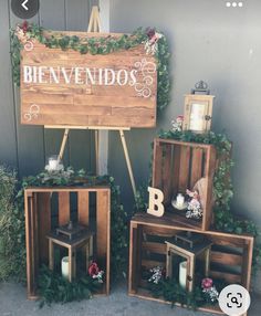 three wooden crates with flowers and candles on them sitting in front of a sign that says benvendos