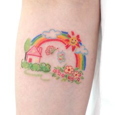 a small tattoo on the arm of a person with a house and rainbow in the background