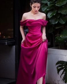 a woman in a pink dress is standing outside