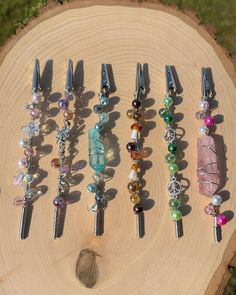 several different colored beads and hair pins on a piece of wood with grass in the background