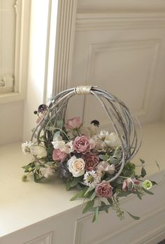 a flower arrangement sitting on top of a white counter next to a window sill