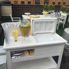 an ice chest is set up with drinks and lemonade on the outside patio table