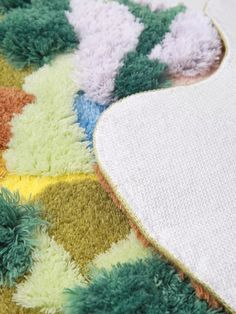 an area rug with various colors and designs on it, including green, yellow, blue, white and pink