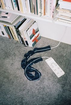 a video game controller laying on the floor next to a book shelf