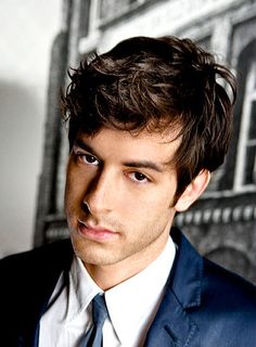 a close up of a person wearing a suit and tie with a serious look on his face