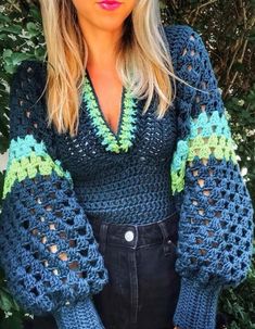 a woman wearing a blue crochet sweater with green trim