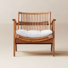 a wooden chair with a white pillow on it's back and armrests