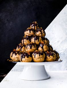 a stack of cookies with chocolate drizzled on top sitting on a white cake plate