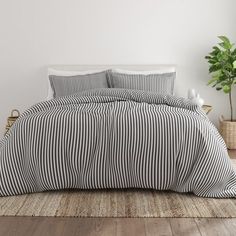 a black and white striped comforter on a bed with a potted plant in the corner