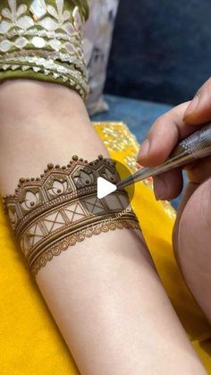 a woman is doing henna on her arm