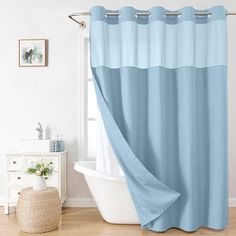 a bath tub sitting next to a window covered in blue shower curtaines and rugs