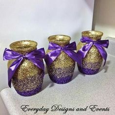 three gold and purple vases with bows on them are sitting on a white surface