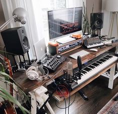 a computer desk with musical equipment on it and a keyboard in front of the monitor