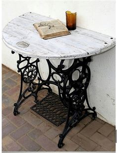 an old sewing machine table with a book on it's top and a candle next to it