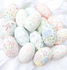 a pile of painted eggs sitting on top of a white cloth covered tablecloth next to each other