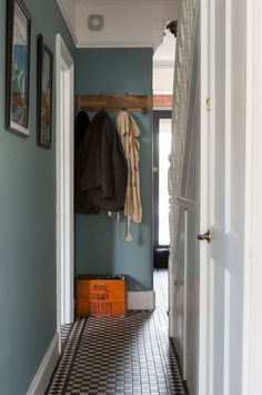 a hallway with blue walls and black and white checkered flooring, coat rack on the wall