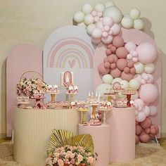 there are many balloons and desserts on the table in front of this wall that is decorated with pink flowers