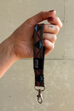 a hand holding a lanyard with a black and red design on it