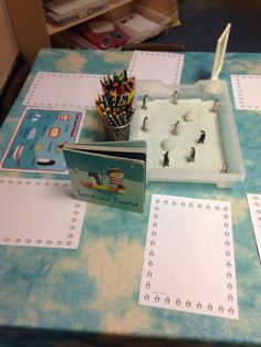 a blue table topped with lots of writing paper and pencils on top of it